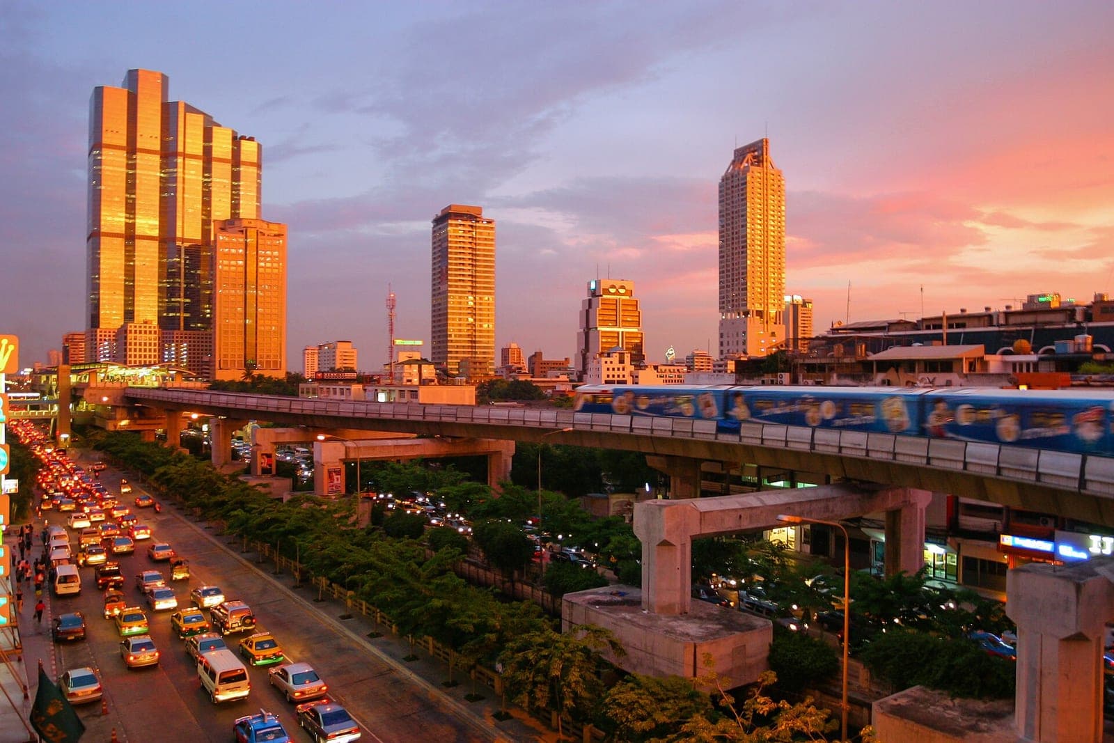 BTS Skytrain passing above Sukhumvit Road traffic at sunset