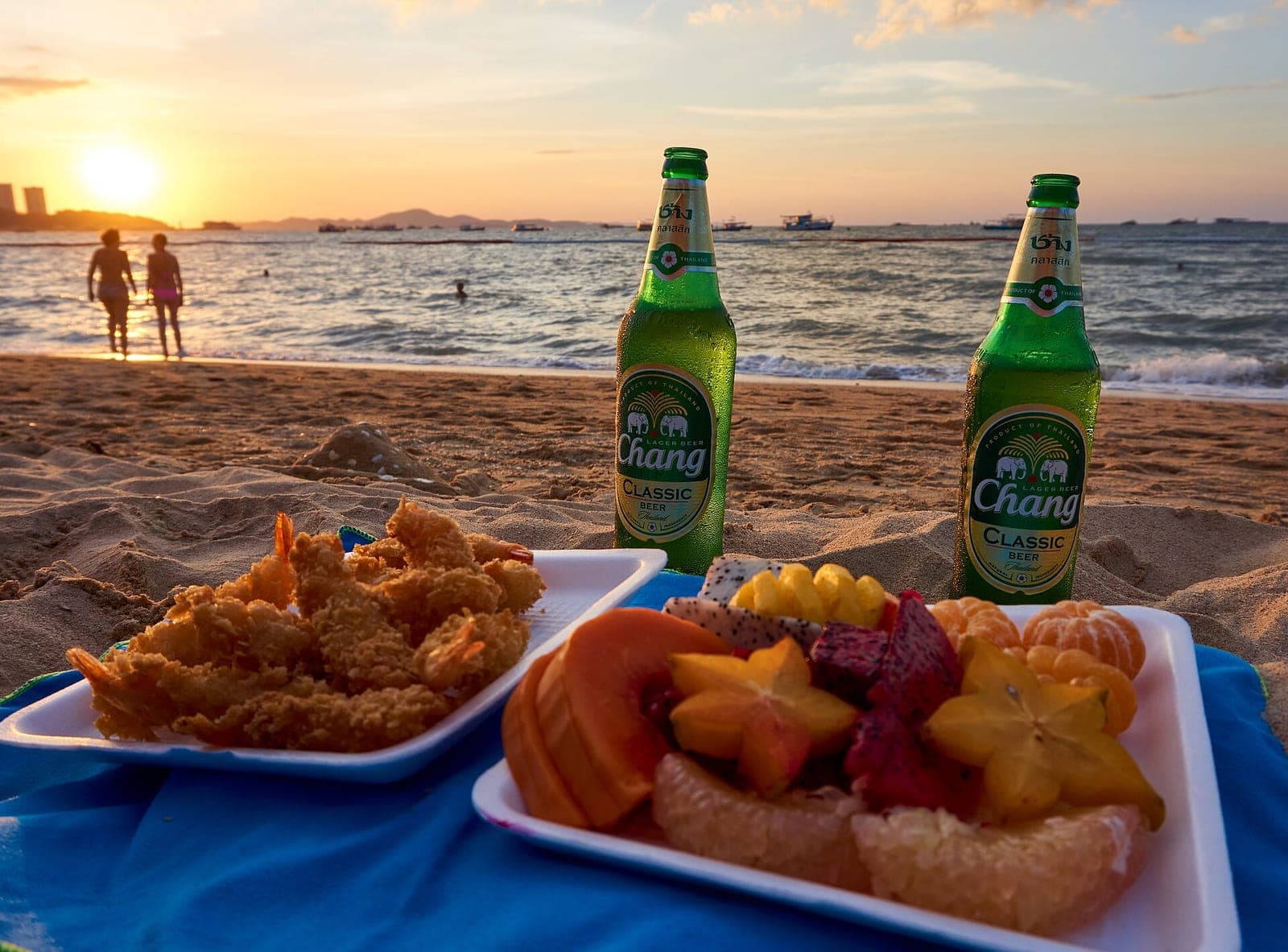 Two bottles of Chang beer and snacks on Pattaya Beach at sunset