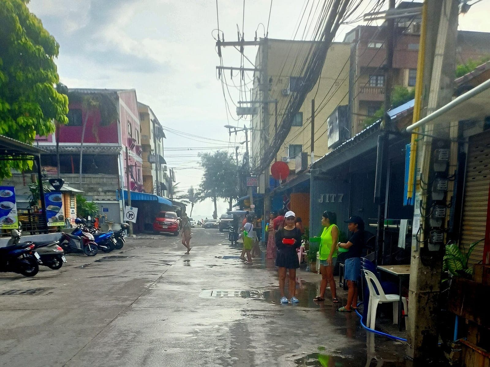 People with water guns on a wet side street in Pattaya during Songkran, April 2025
