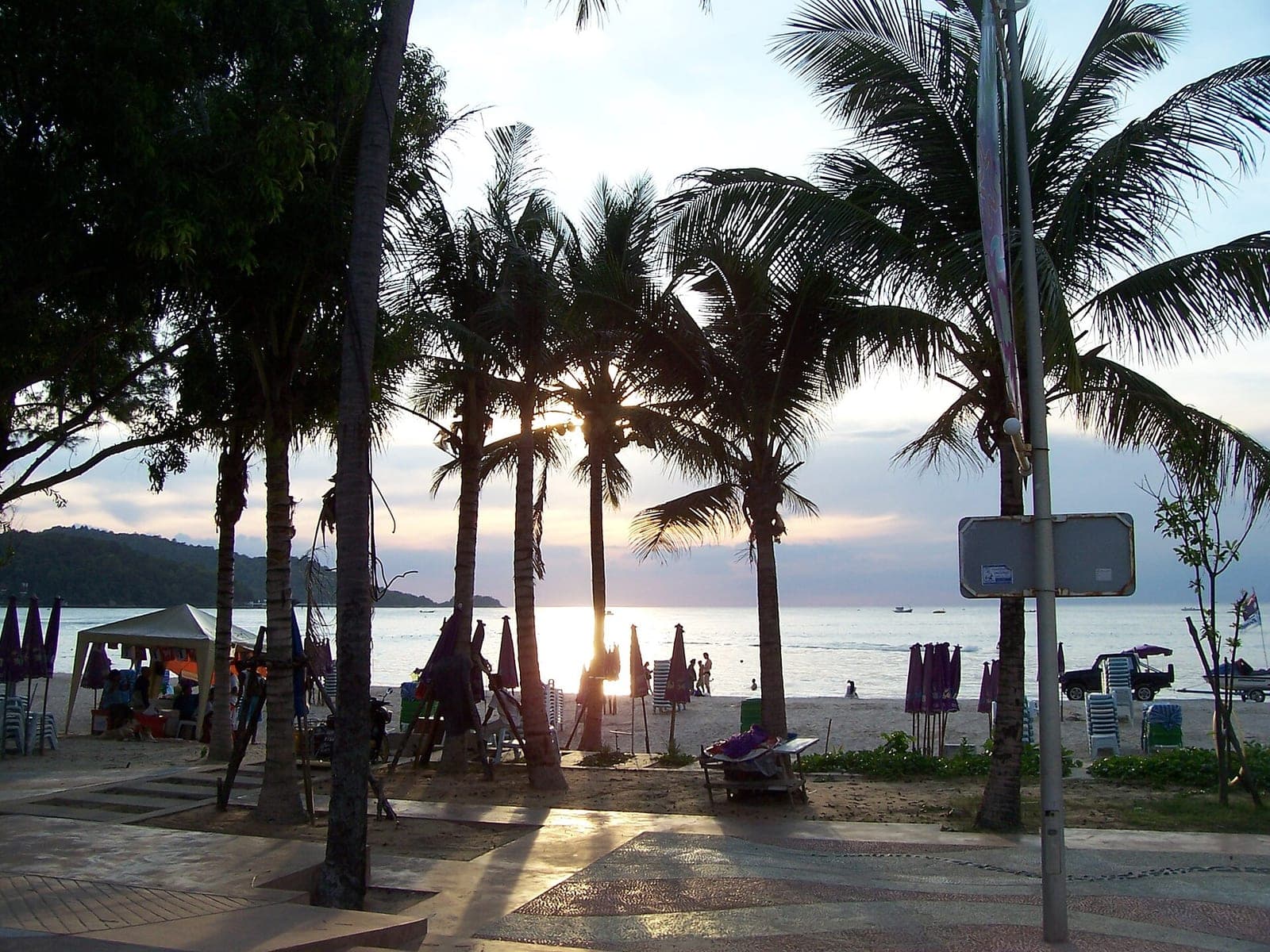 Palm trees and beach umbrellas on Patong Beach, Phuket, at sunset